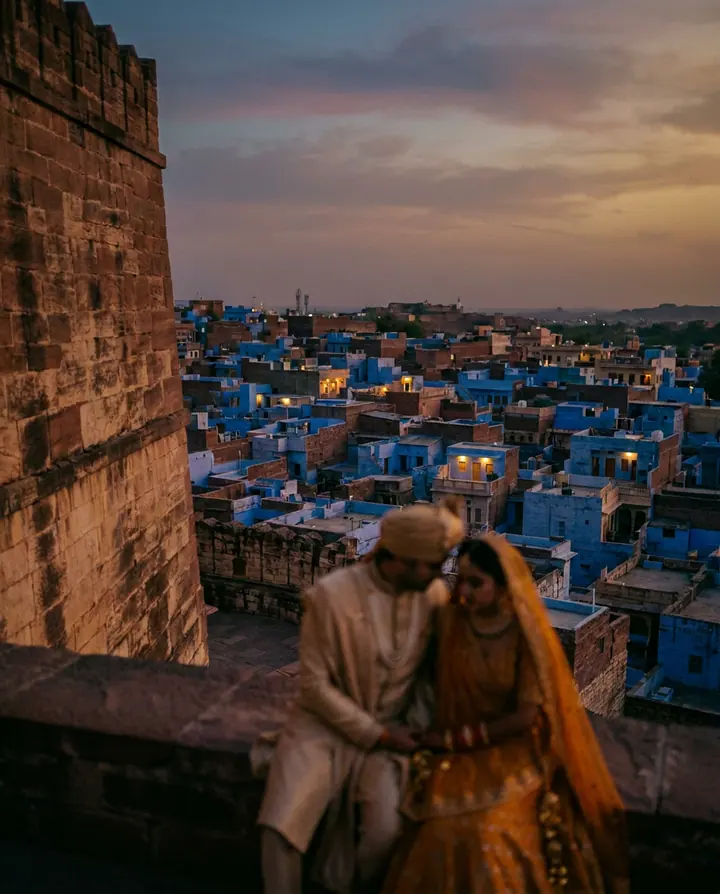 The blue city of Jodhpur below a fort wall at dusk.