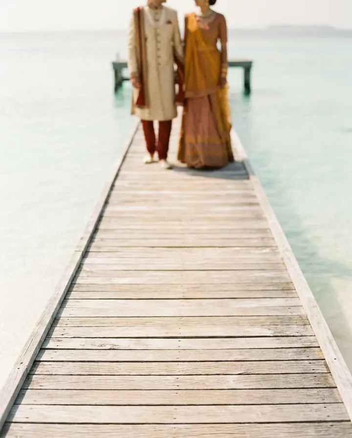 A timber jetty over pale shallow water in the Maldives.