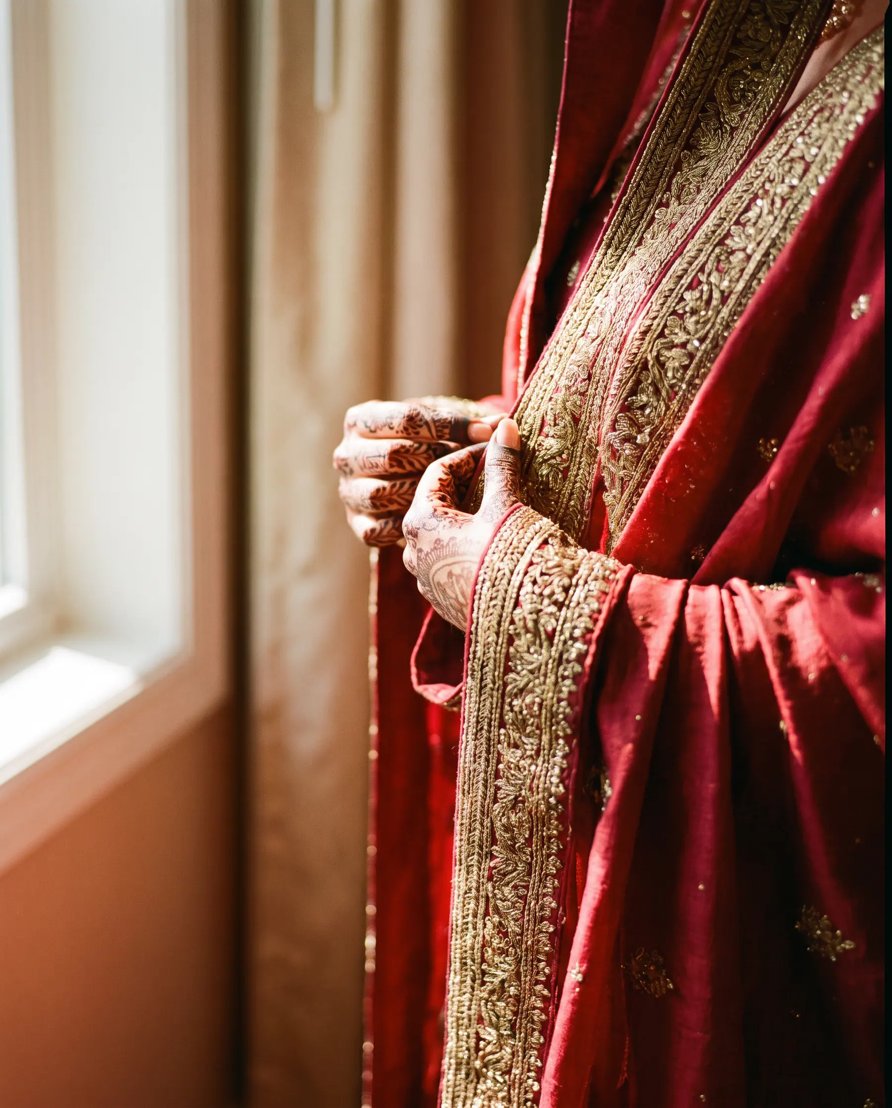 A bride's hands holding a dupatta edge heavy with gold work.
