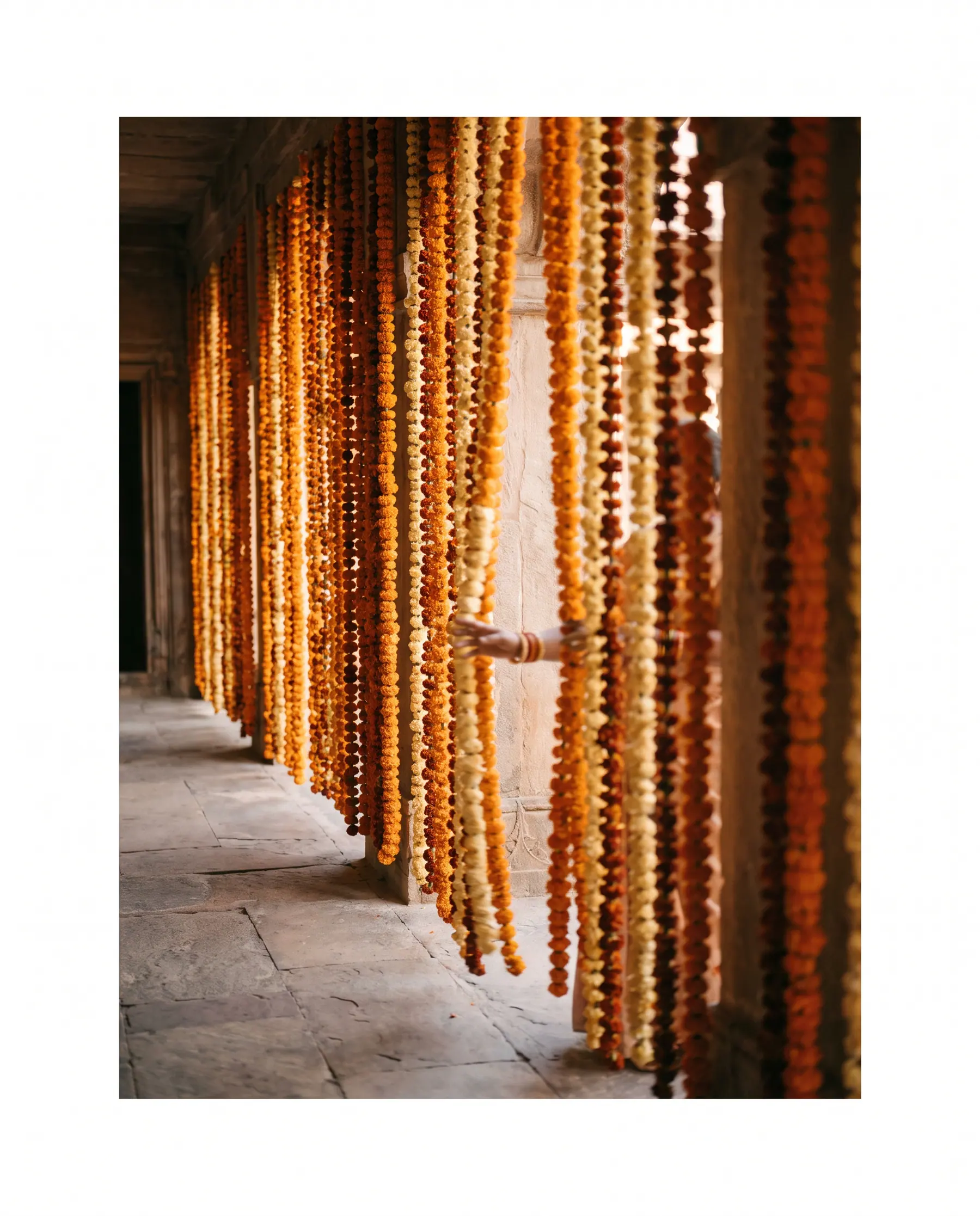 Marigold strands hung floor to ceiling in a stone corridor.