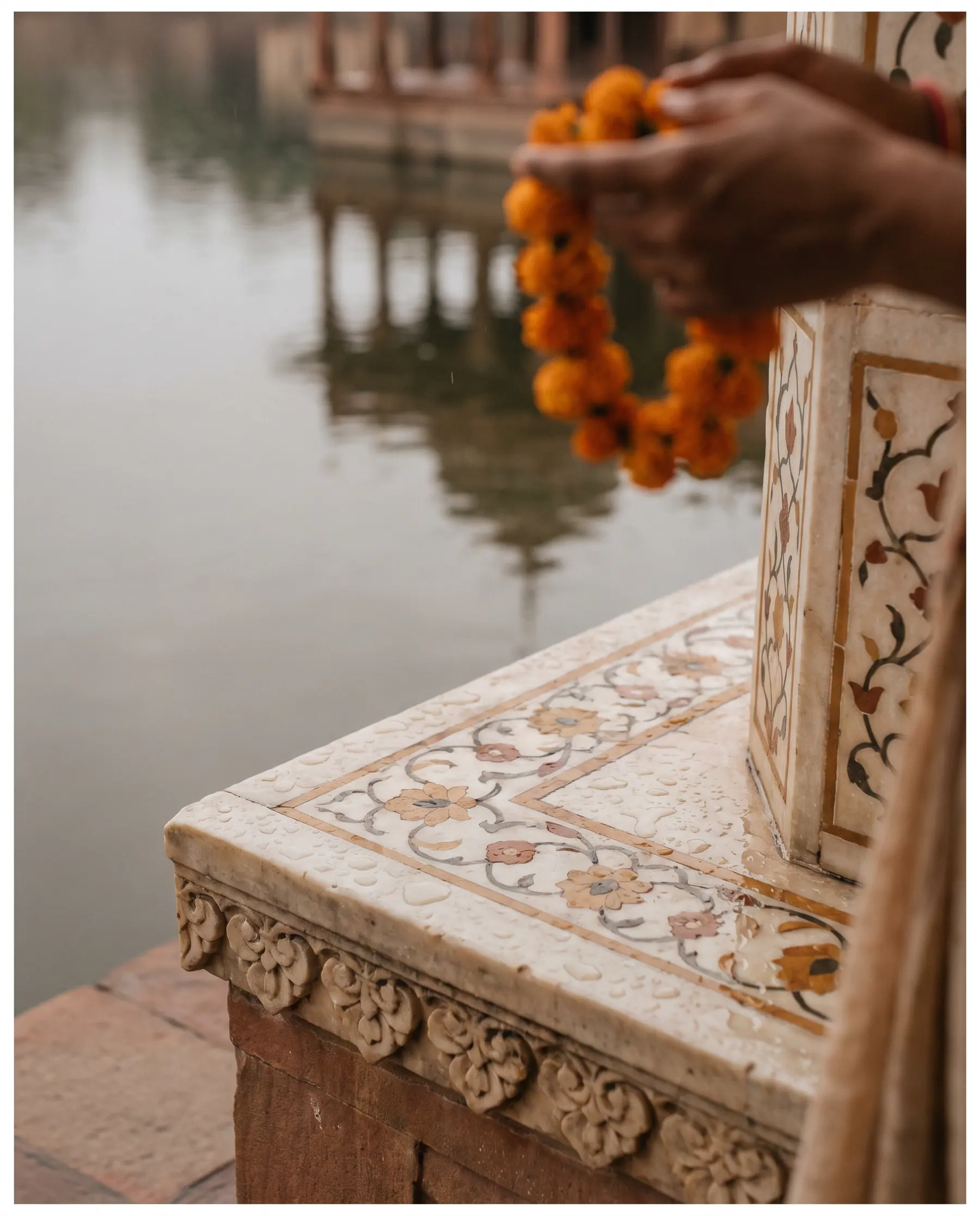 Rain beading on marble inlay beside still lake water.